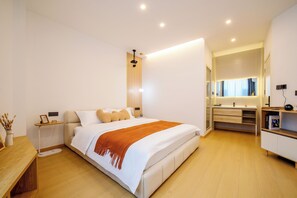 A modern bedroom with a bed, bedside tables, a nightstand, a wooden bench, a mirror, and a built-in wardrobe. - Homie Inn (Changsha)