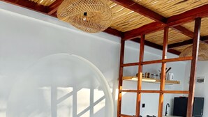 Eine moderne Küche mit Holzbalken, einer hängenden Leuchte und einer eingebauten Sitzecke mit einer Ananas auf dem Tisch.