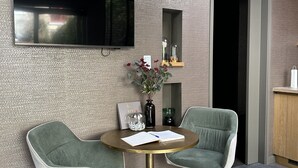 A modern living room with two green chairs, a round table, a mounted flat-screen TV, and a built-in air conditioner. - City Oasis The Hague, in the heart of The Hague with private parking (The Hague)