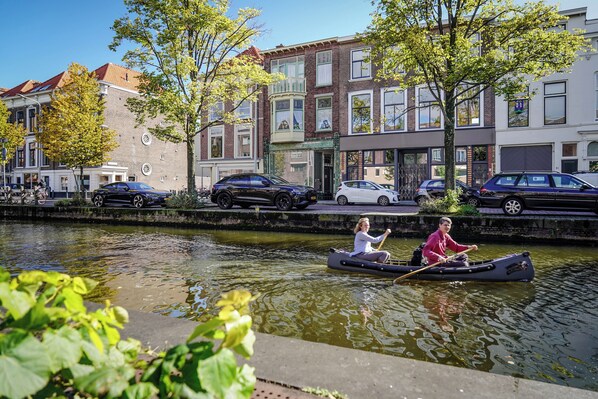 A canal with two people in a boat, surrounded by buildings with distinct architectural styles. - City Oasis The Hague, in the heart of The Hague with private parking (The Hague)