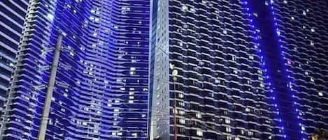 A high-rise building with a modern architectural design, featuring a prominent vertical light strip on one side.
