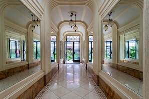 Un'imponente galleria con pavimenti in marmo, ampie finestre e colonne decorate.