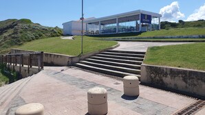 Un edificio moderno con fachada de vidrio, asientos exteriores e izamiento de bandera.