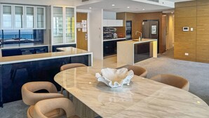 A modern hotel lobby with a marble reception desk, comfortable seating, and a view of the ocean.