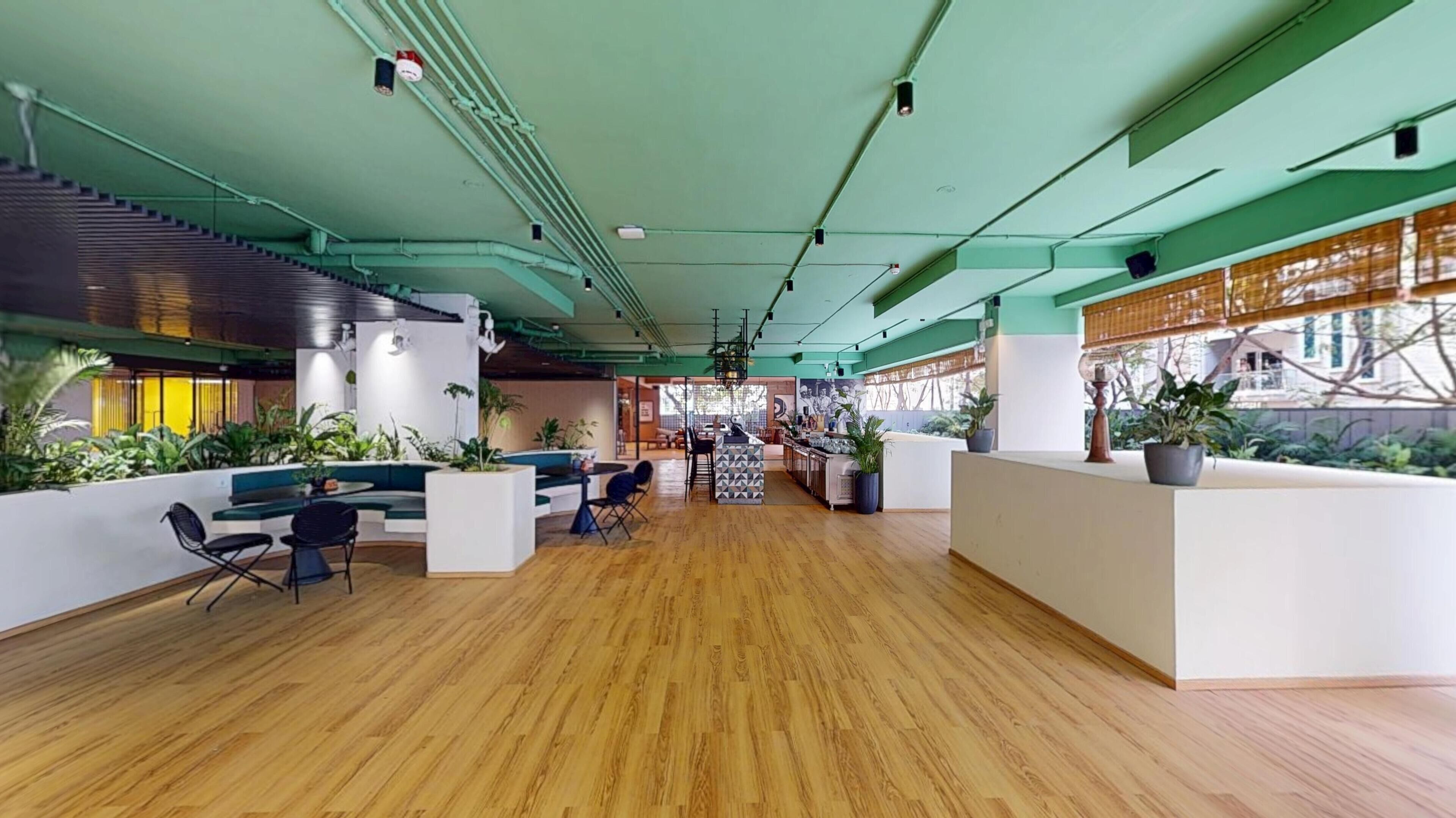 A spacious lobby with a wooden floor, seating areas, and a reception desk.