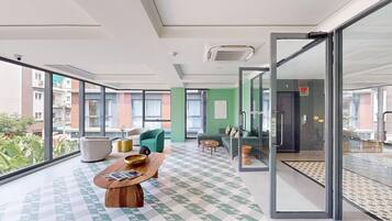 Een modern interieur met een zwart-wit geruite vloer, een houten bijzettafeltje en groene banken.