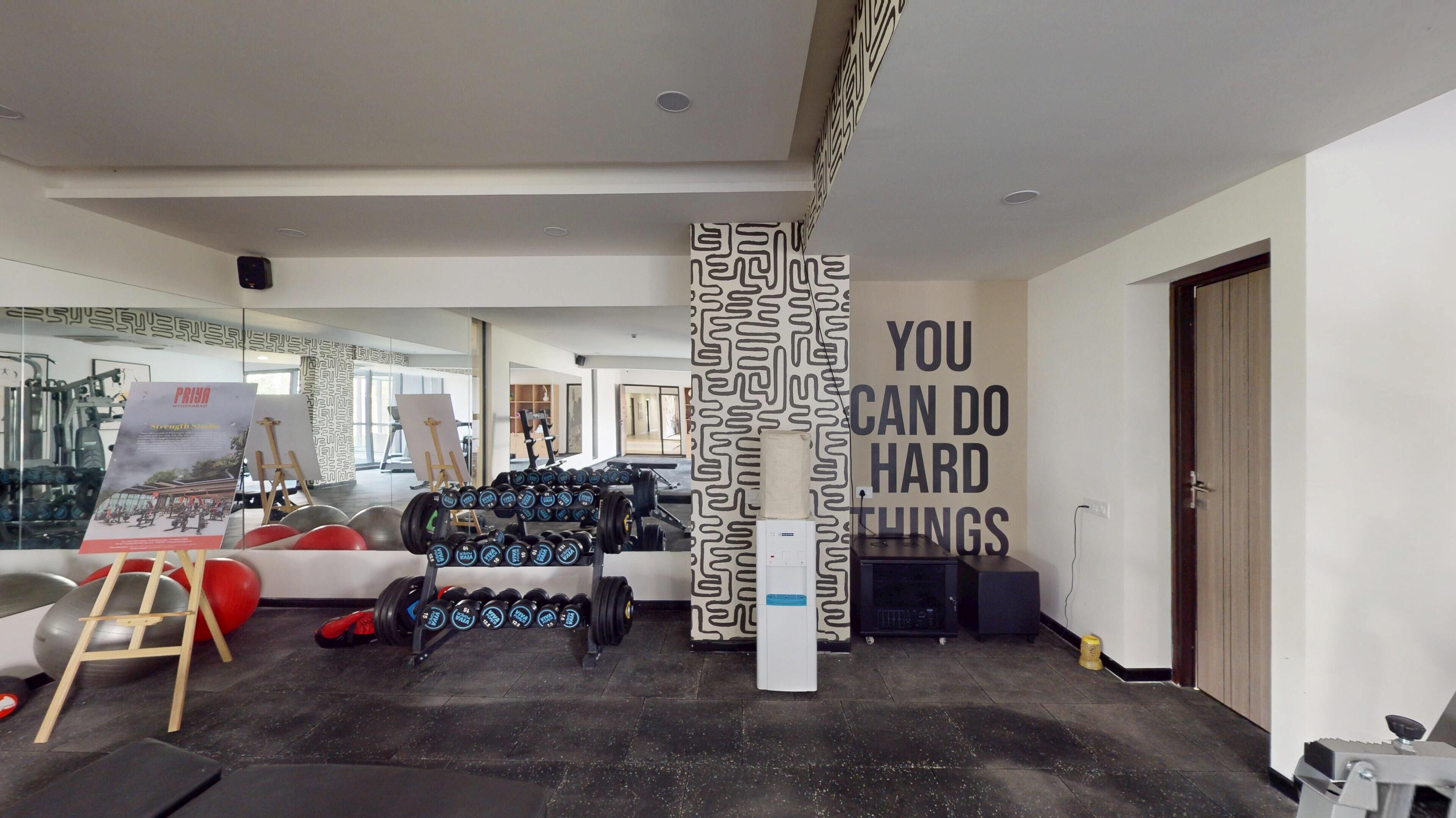 A gym with exercise equipment, motivational wall art, and a mirror reflecting the space.