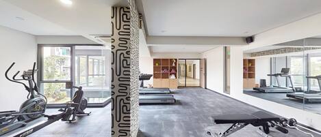 Un gimnasio moderno con cintas de correr, elípticas y una prensa de banca.