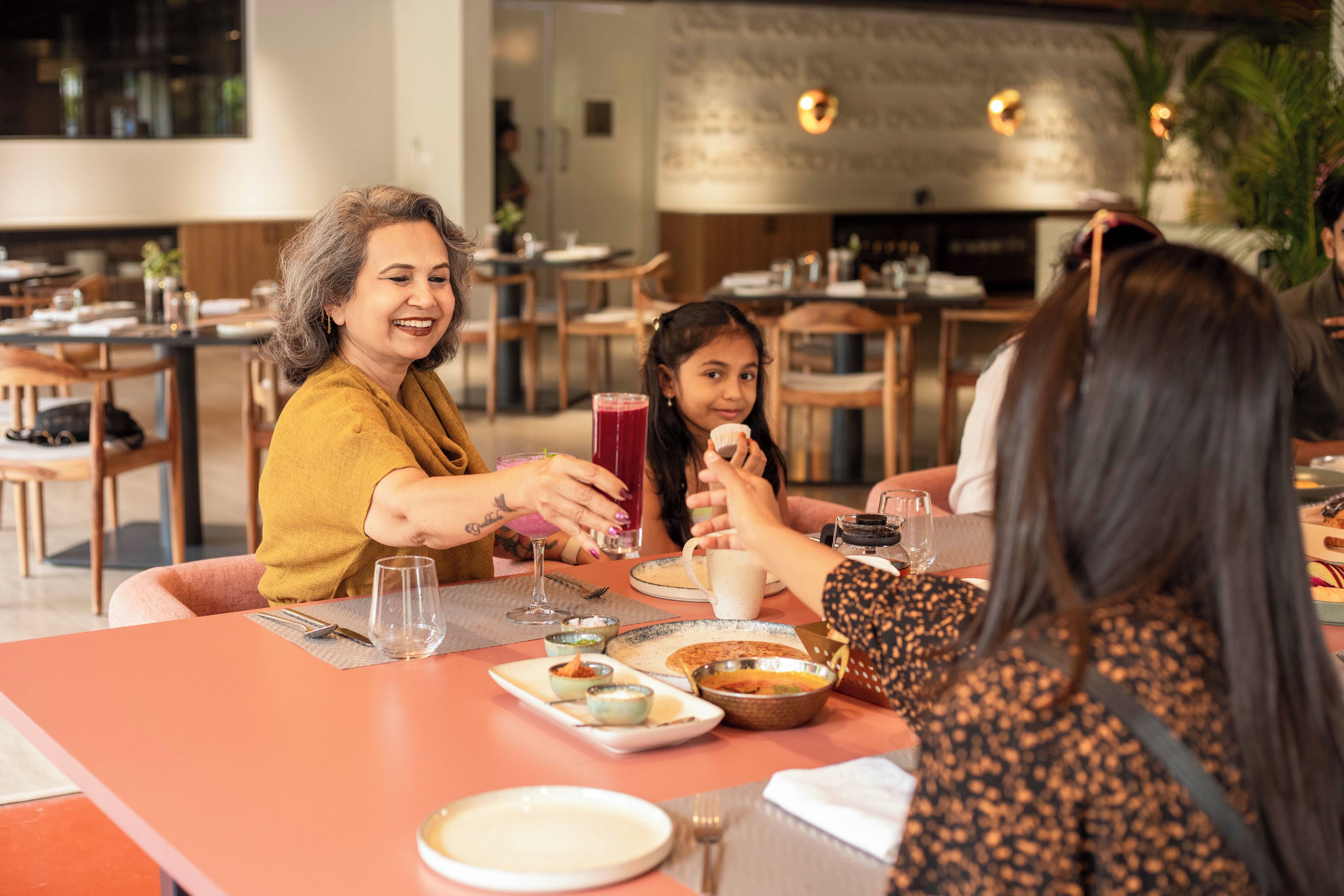 A group of people dining in a restaurant with tables set for meals, glasses, and a variety of dishes.
