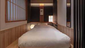 A neatly arranged room with a bed, a wall-mounted shelf, and a window with vertical blinds. - ENSO TOKYO AKASAKA - Hostel (Tokyo)