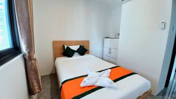 Una camera d'albergo con un letto, una finestra con tende, un condizionatore d'aria e un armadio.