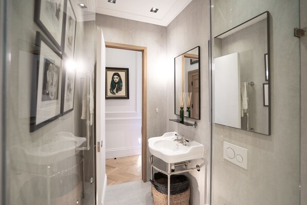 A modern bathroom with a glass shower enclosure, a white sink, and a large mirror. - Cadogan Square - 2 Bedroom Apartment V (London)