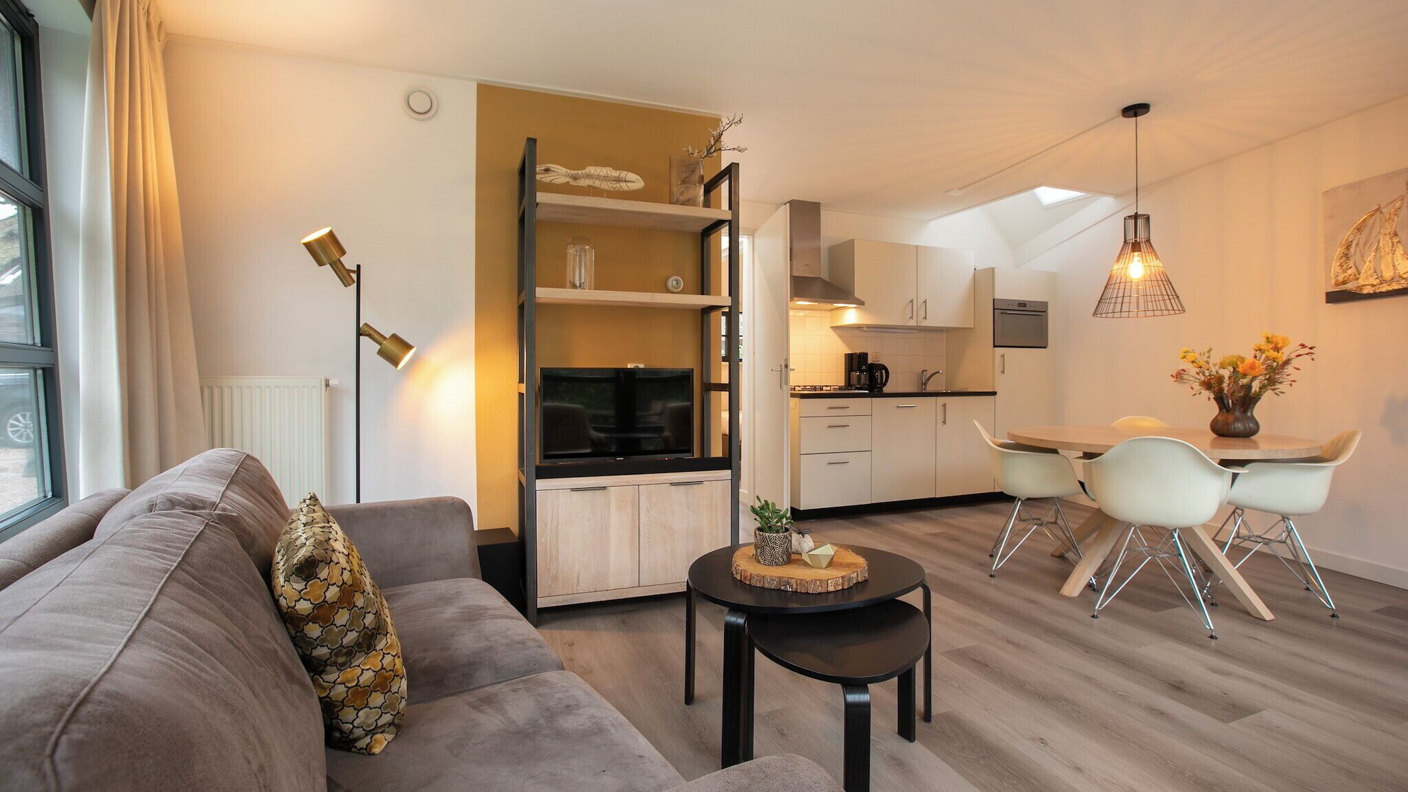 A modern living room with a sofa, a coffee table, and a dining area with chairs and a table.