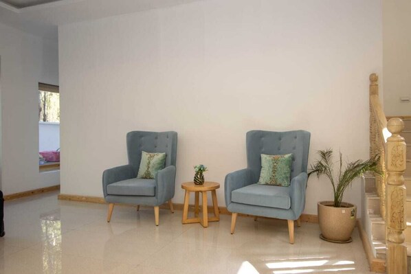 Una habitación con dos sillones azul claro, una mesita de madera y una planta en maceta.