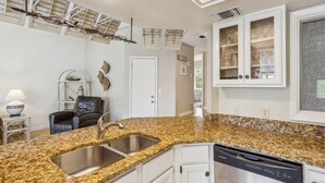 A kitchen with granite countertops, stainless steel sink, white cabinets, and a built-in dishwasher.