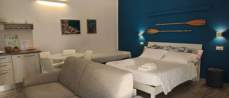 A modern bedroom with a large bed, a sofa, and a small table.