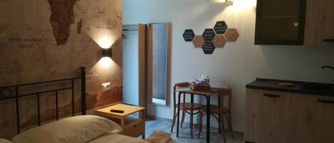 Habitación de hotel con cama, escritorio, silla, una mesita, televisor montado en la pared y un mapa en la pared.