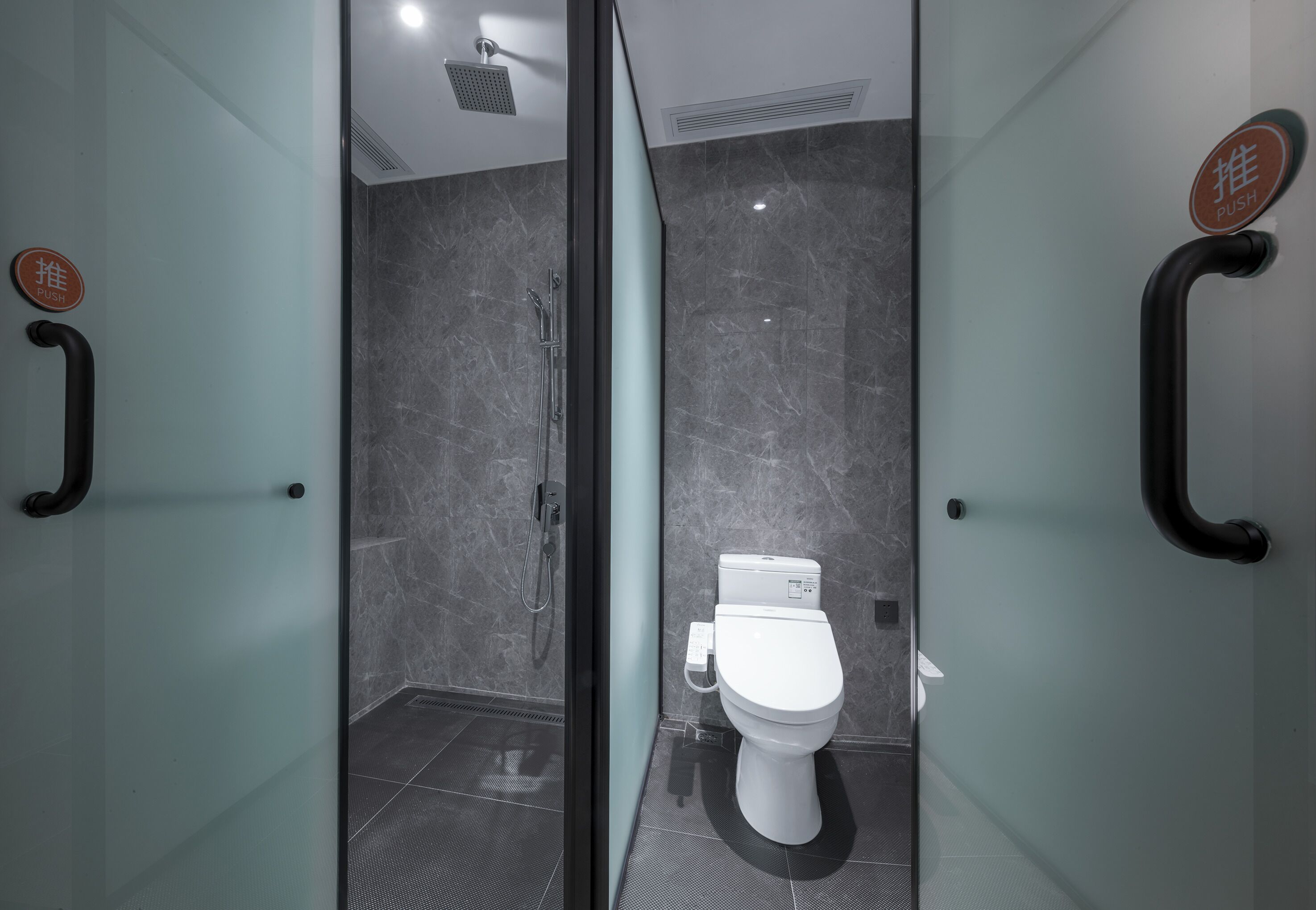 Een moderne badkamer met een glazen douchewand, een douche en een toilet.
