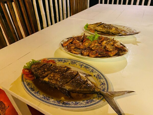 A dining table with three plates of seafood, including whole fish and shrimp, on a white tablecloth. - New Casa Marc (Induruwa)