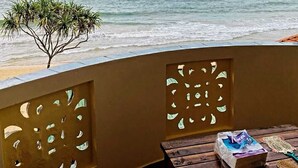A balcony with a view of the ocean, a small tree, and a table with a package and a decorative item. - New Casa Marc (Induruwa)