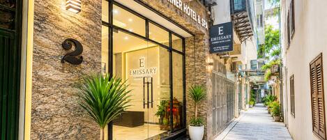 A hotel entrance with a stone facade, glass doors, and potted plants.