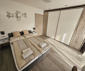 Une chambre moderne avec deux lits, une armoire, une table de chevet et un élément décoratif mural.