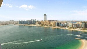 A coastal cityscape with a prominent tower, a marina, and a beach. - Coastal Elegance 1-Bedroom in Grand Bleu (Emaar Beachfront)