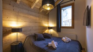 A wooden cabin bedroom with a bed, two lamps, and a window.