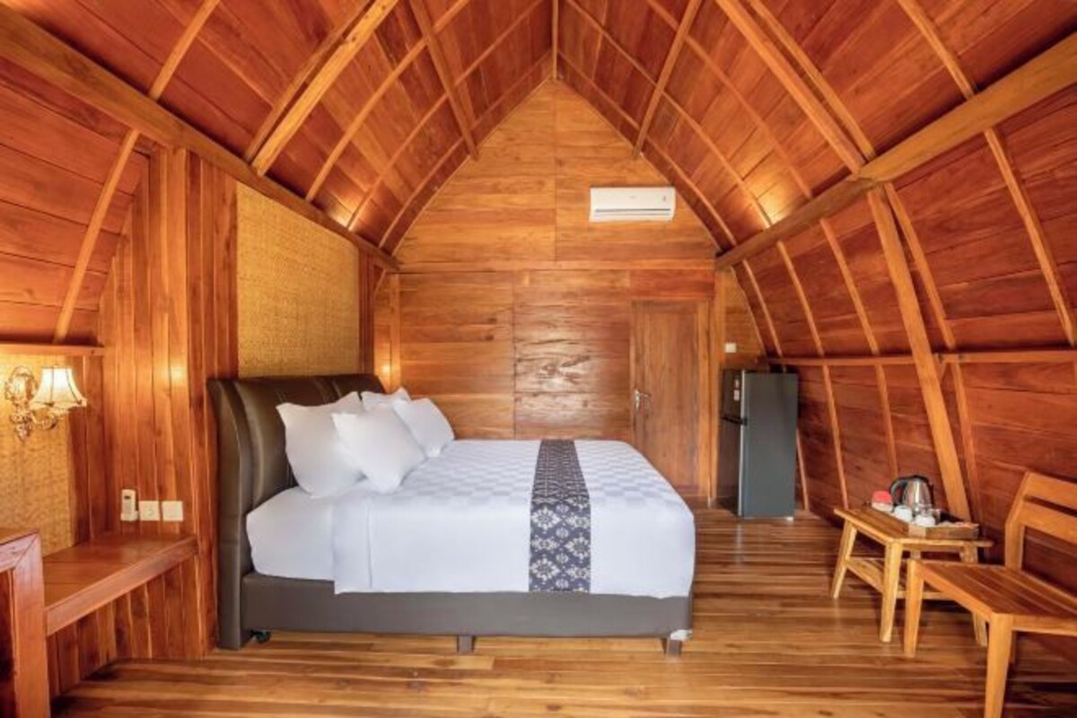 A wooden room with a bed, a desk, and a chair.