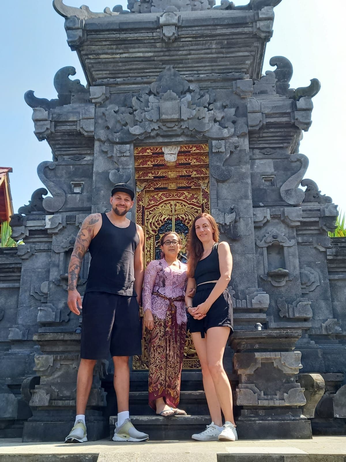 Un grupo de personas frente a una construcción de piedra con intrincados grabados y una puerta grande y ornamentada.