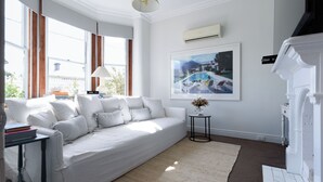 A modern living room with a white sofa, a small side table, and a framed picture on the wall.