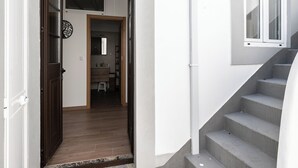 A staircase leading to a second floor, a wooden door, and a view into a room with a window and a small stool. - Aldon Apartment, Tavira, Algarve (Tavira)