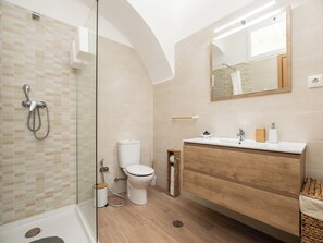 Une salle de bain moderne avec une douche à parois de verre, des toilettes et un meuble-lavabo avec un miroir.