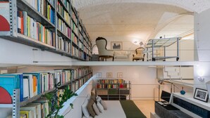 A multi-level library with bookshelves, a reading area with a sofa, and a staircase. - L Angolo del Libro by Wonderful Italy (Turin)