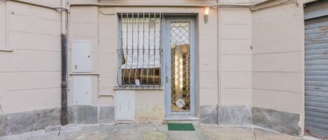 A building with a gated entrance, a small balcony with decorative railings, and a garage door.
