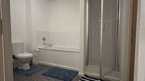 Une salle de bain équipée de toilettes, d’une baignoire et d’une douche.