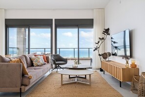 Un salon moderne avec un canapé, une table basse ronde et un téléviseur fixé au mur.