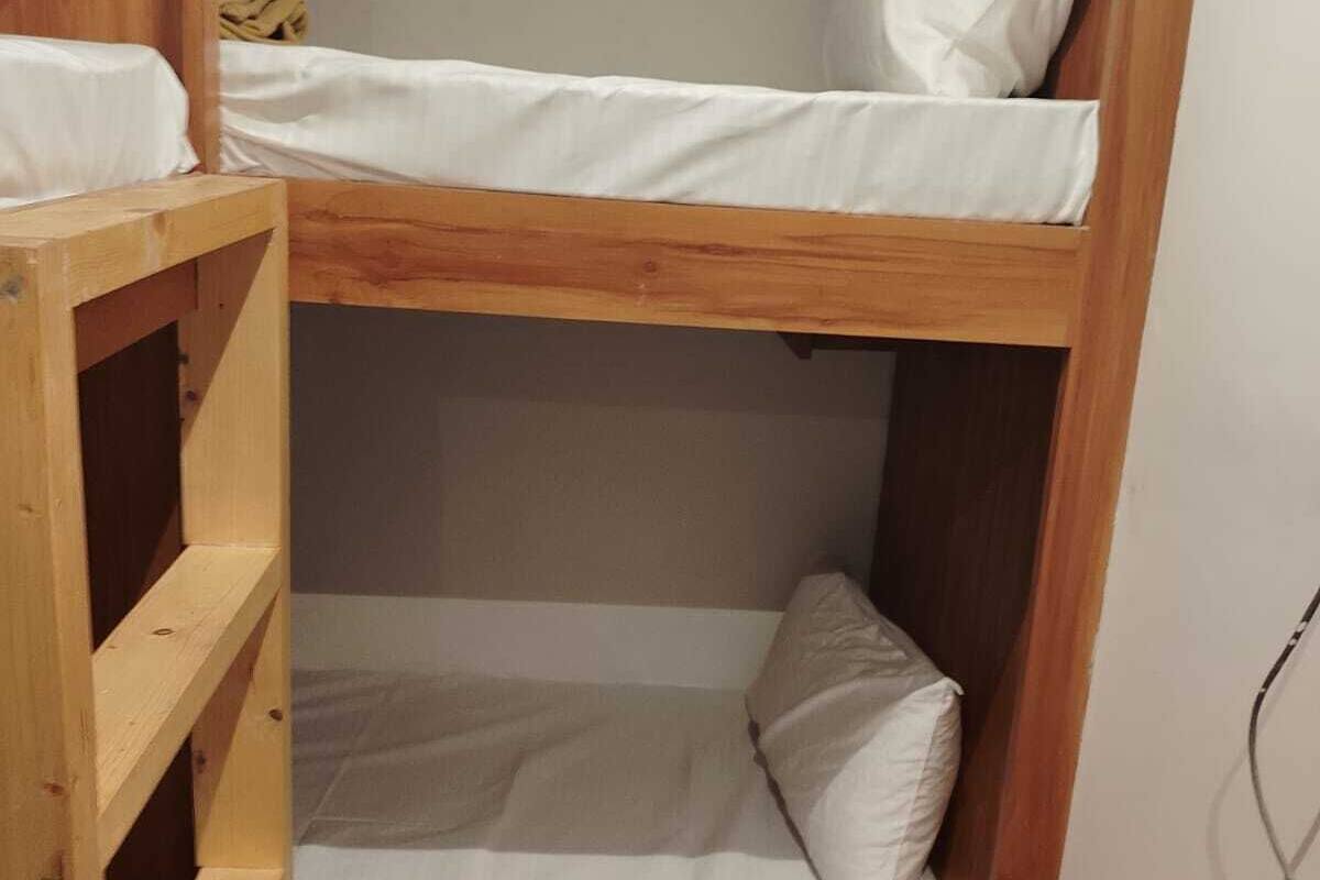 Egy emeletes ágy, fa kerettel és fehér ágyneművel.
