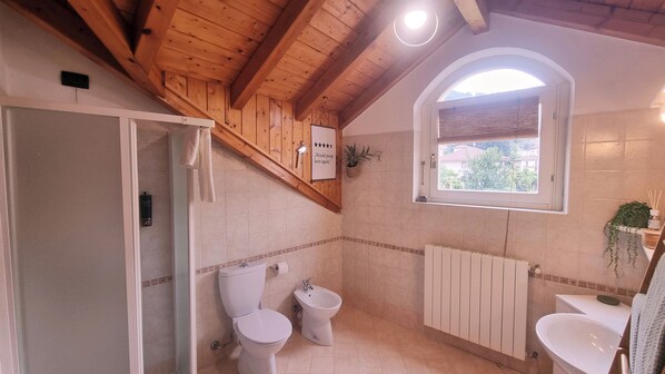 A bathroom with two toilets, a bidet, a radiator, and a window with a view of the outside. - la dolce vita Penthouse - Charm in Heart of Stresa (Stresa)