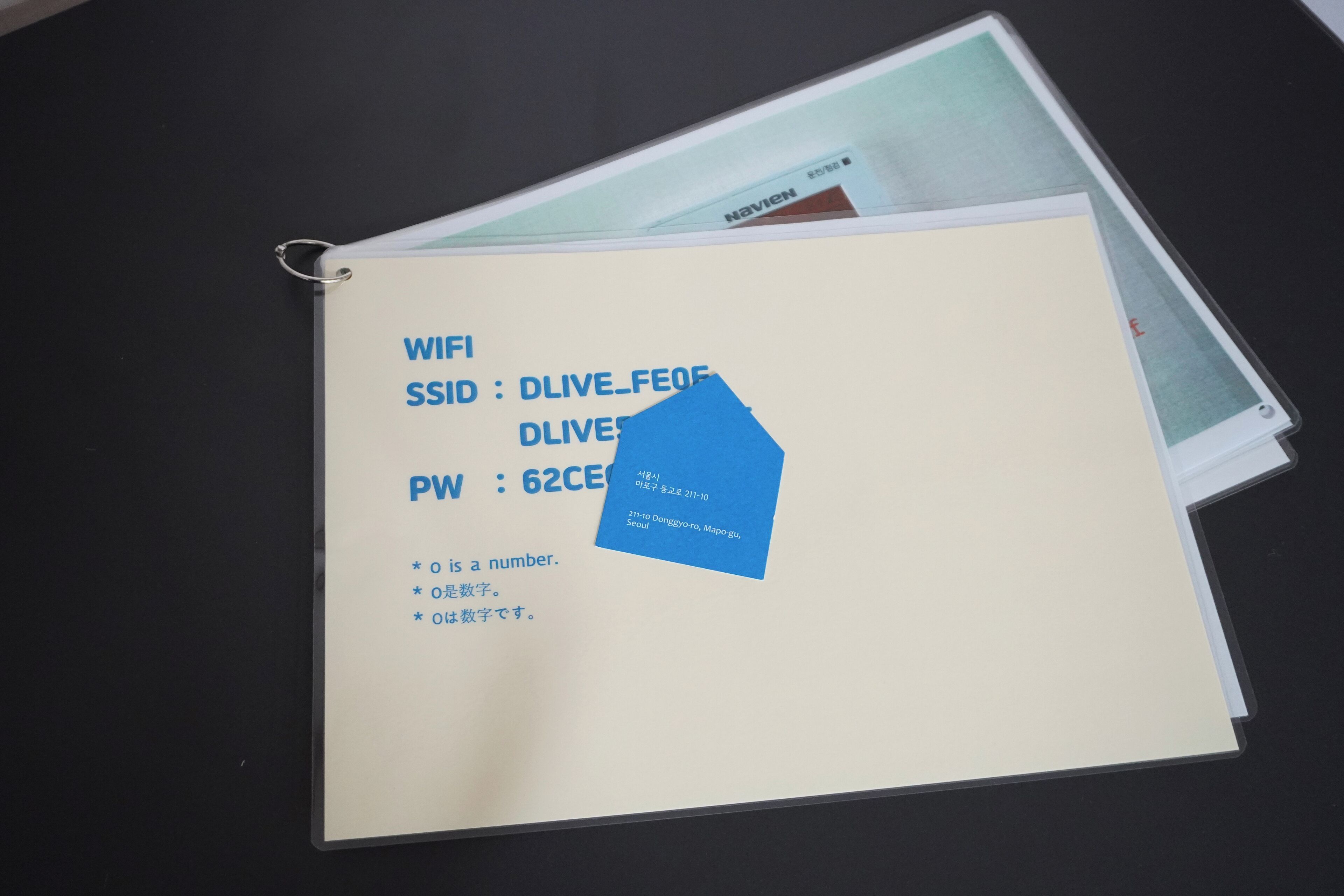 A folder with a label containing WiFi and SSID information, a blue sticky note with text, and a partially visible document.