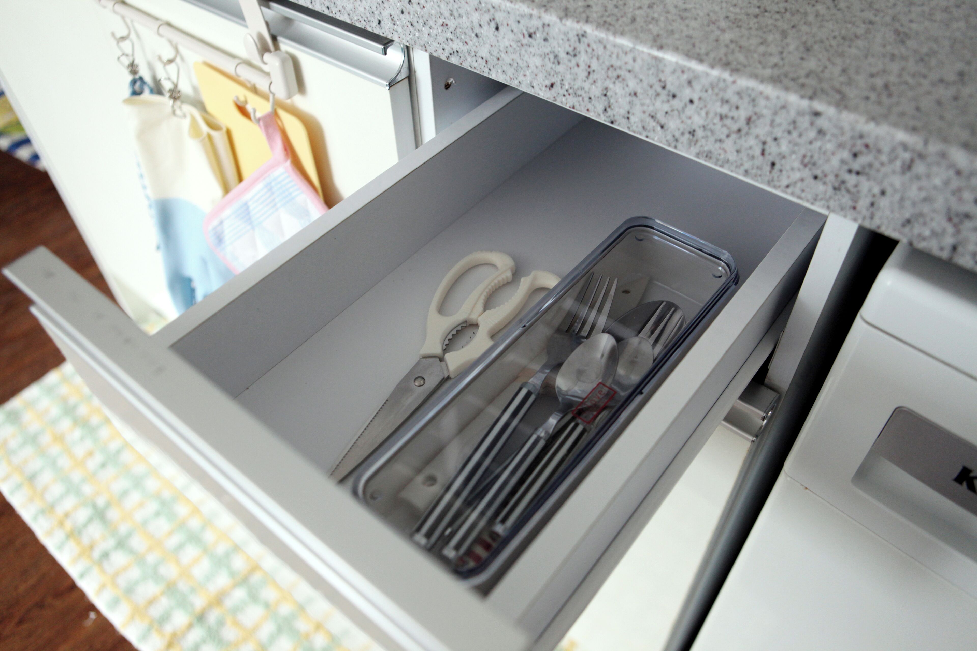 Un cajón de cocina con utensilios y un escurreplatos.