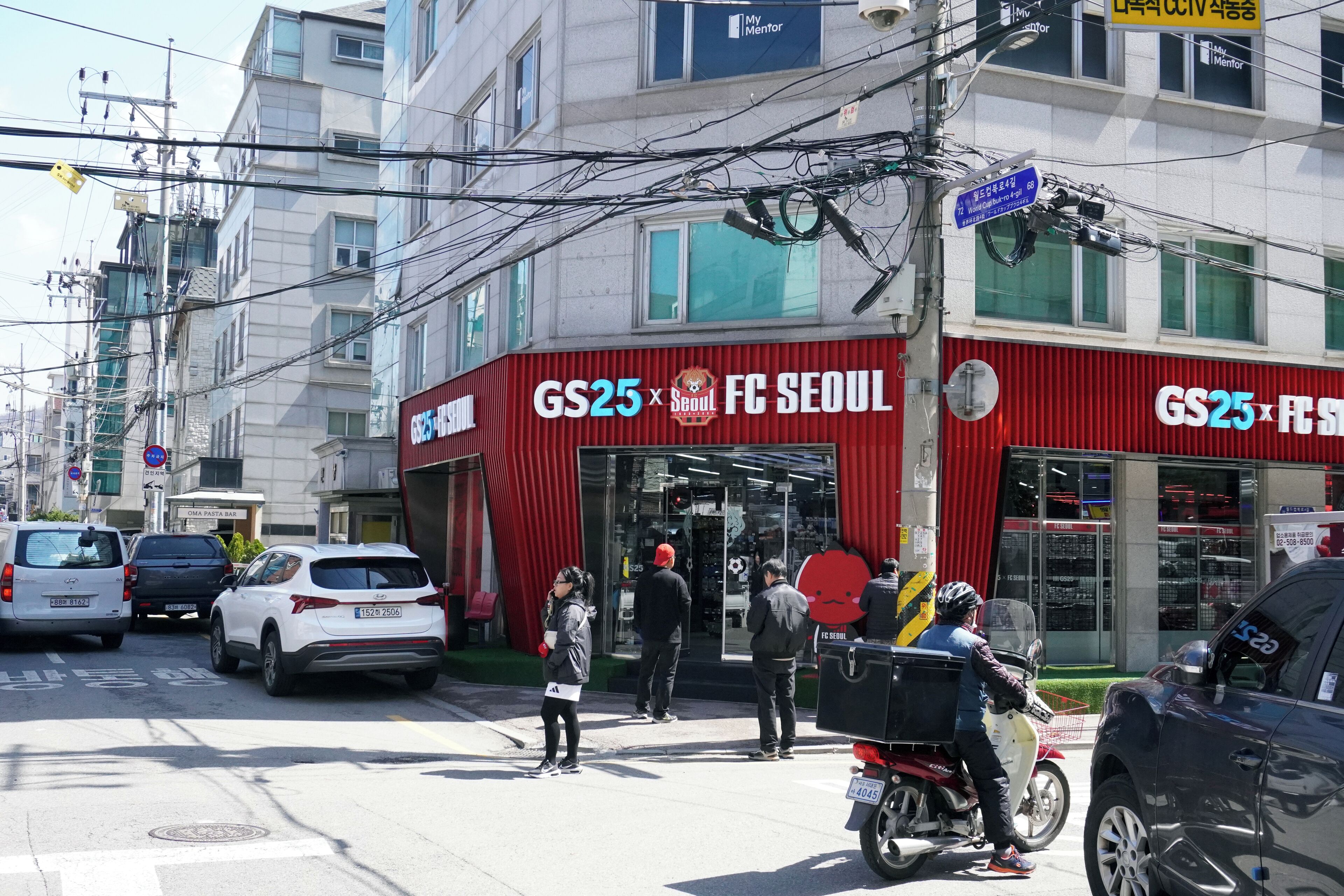 Een gebouw met een rode luifel en borden met de tekst GS25 FC SEOUL.