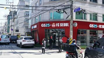 Een gebouw met een rode luifel en borden met de tekst GS25 FC SEOUL.