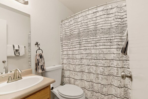 Un baño con lavamanos, inodoro y cortina de ducha.