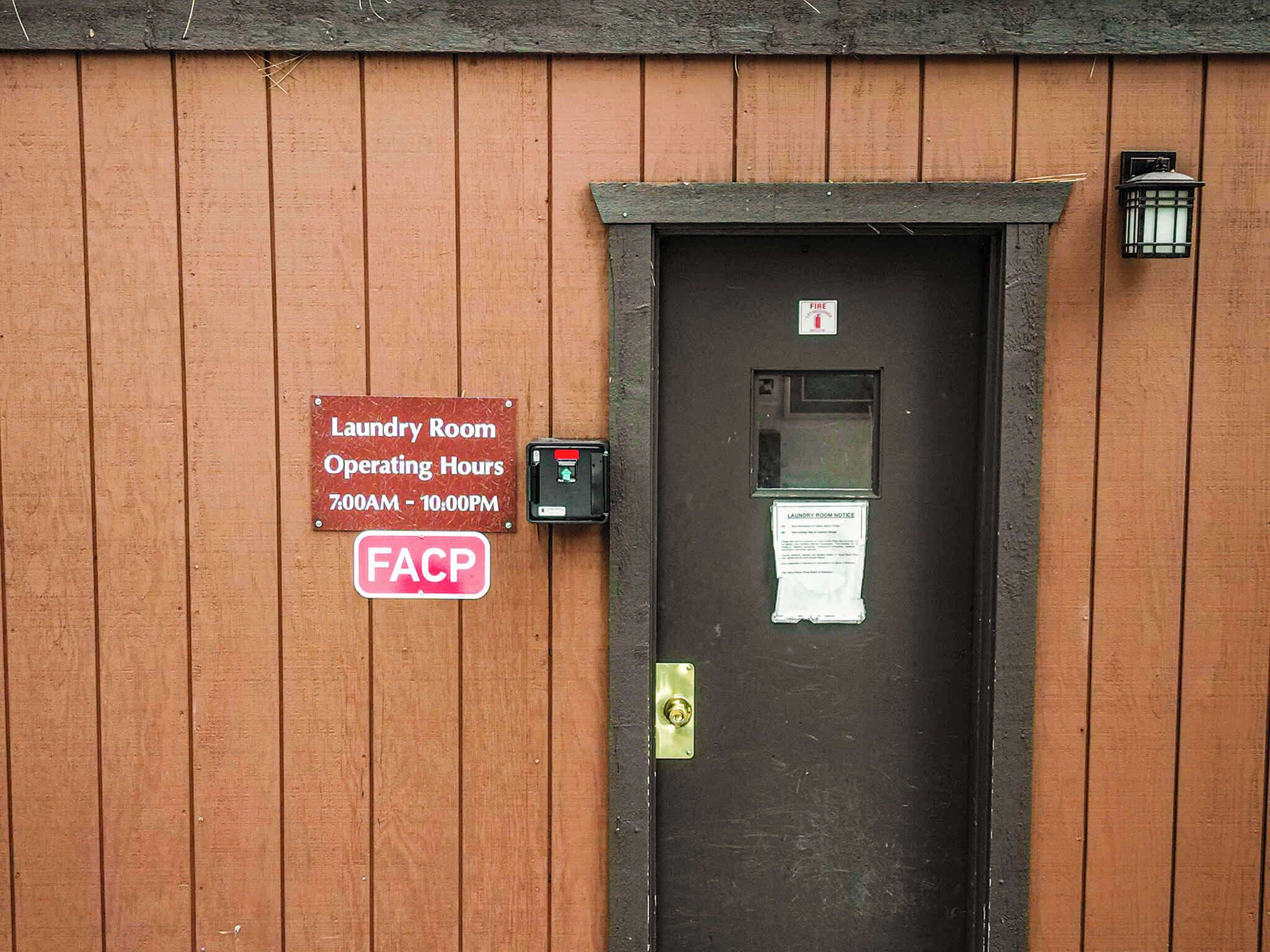 A wooden door with a sign indicating laundry room operating hours and a fire alarm.