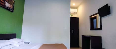 A hotel room with a bed, a desk, a wardrobe, and a mirror.