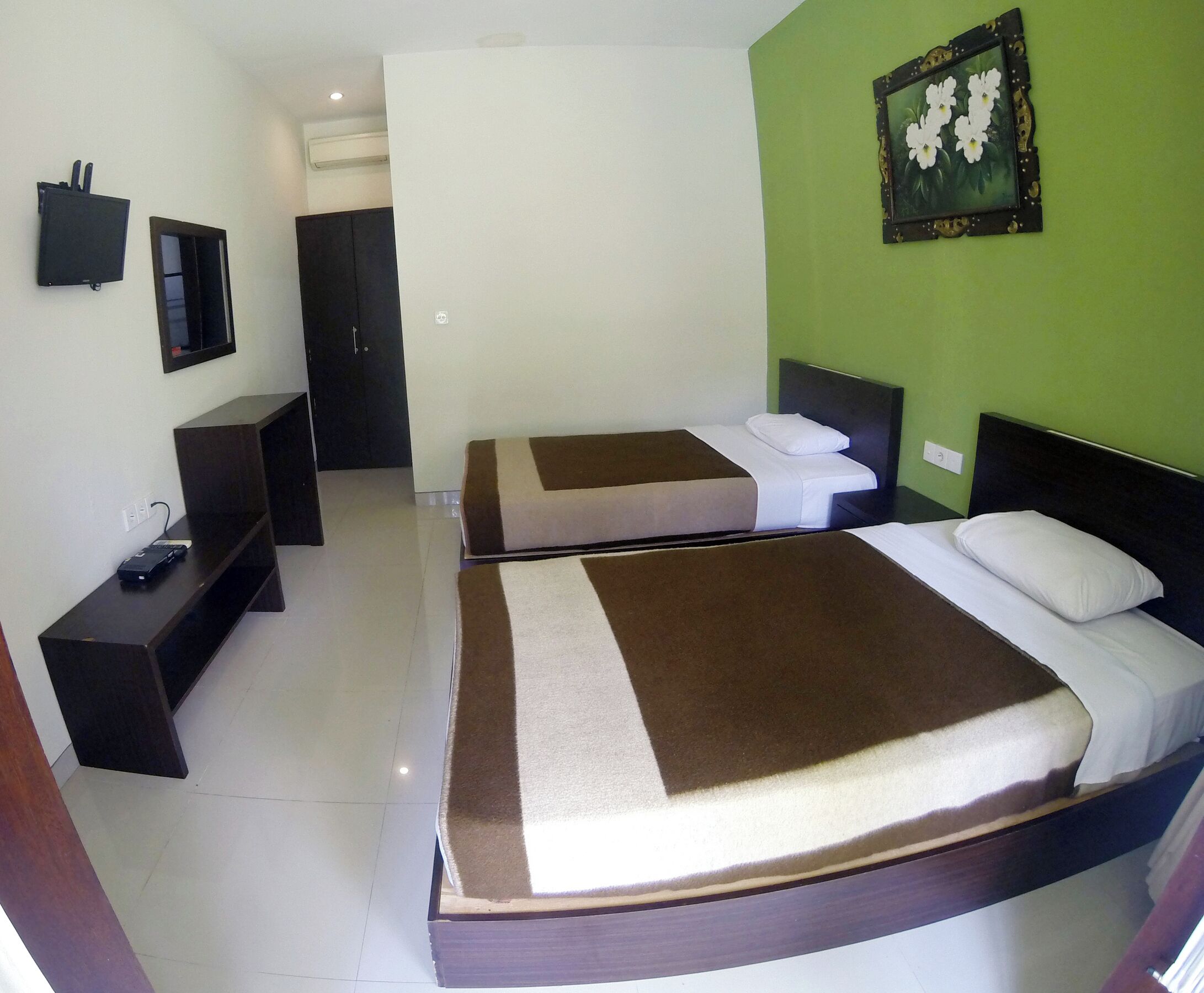 Een hotelkamer met twee bedden, een televisie, een bureau en een groene wand.