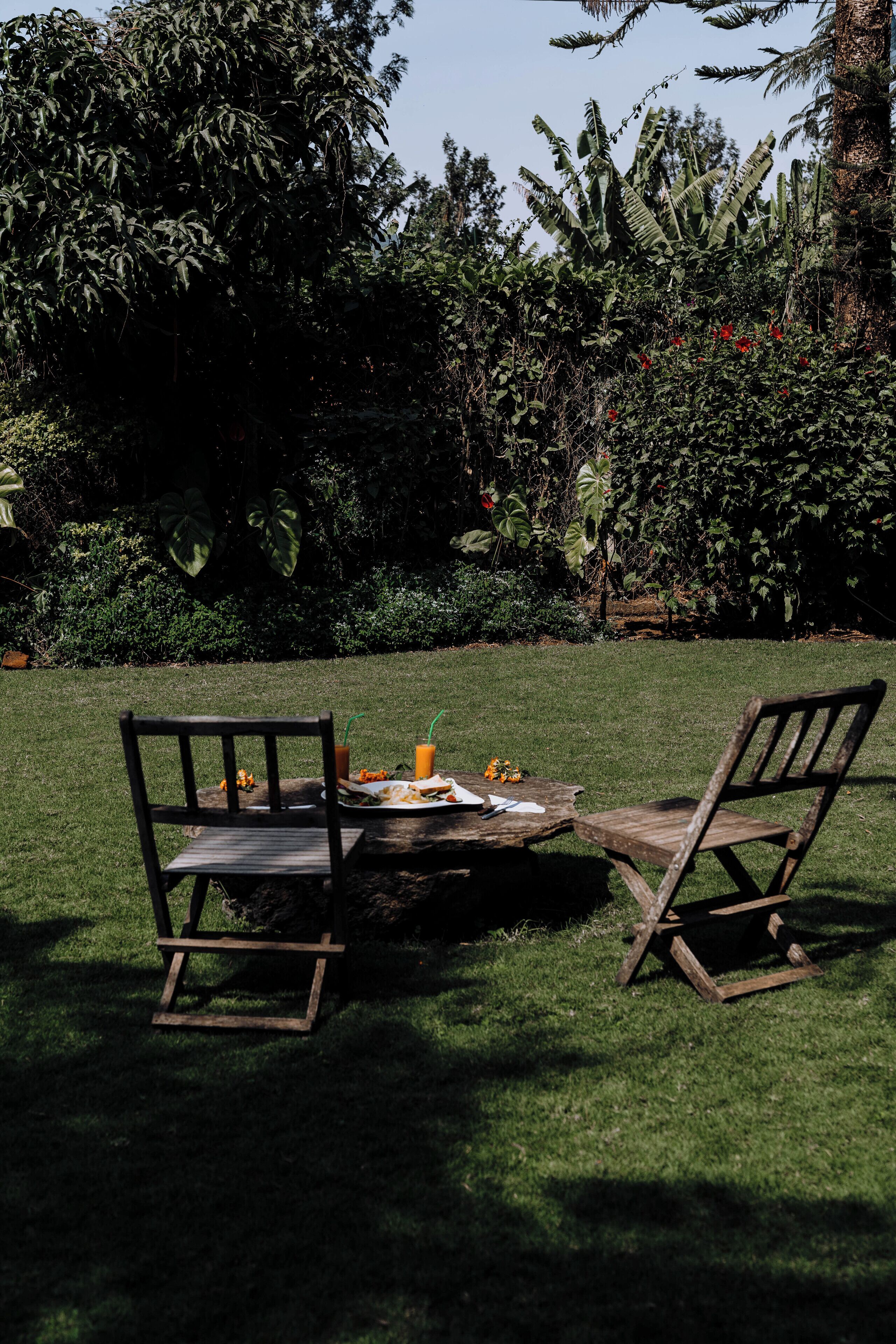 A wooden table with chairs in a garden setting.