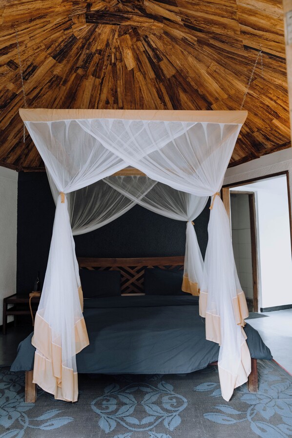 A room with a bed under a canopy, a wooden ceiling, and a patterned floor. - Sanna Eco Lodge (Arusha)