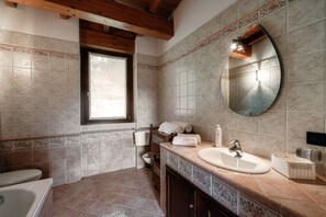 A bathroom with a bathtub, a sink, a toilet, and a window. - Casarico (Maslianico)